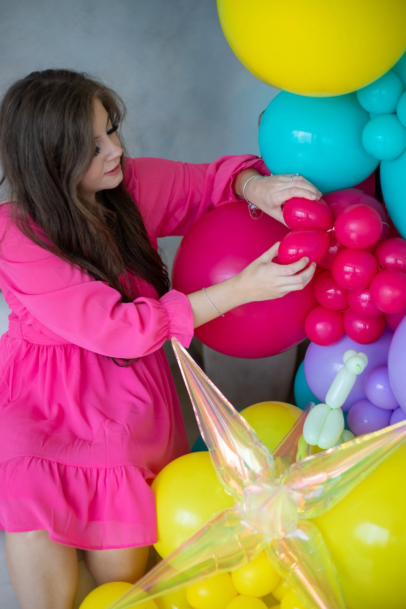 Abbey arranging bright pink and turquoise balloons