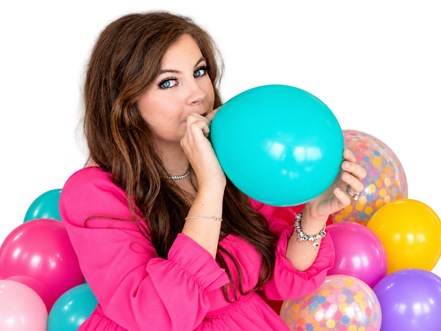 Abbey in pink, blowing up a turquoise balloon surrounded by colorful party balloons